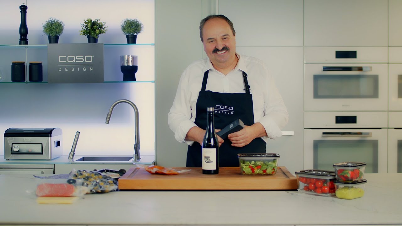 Mann in der Küche mit Essen und Wein, Caso Design Logo im Hintergrund.