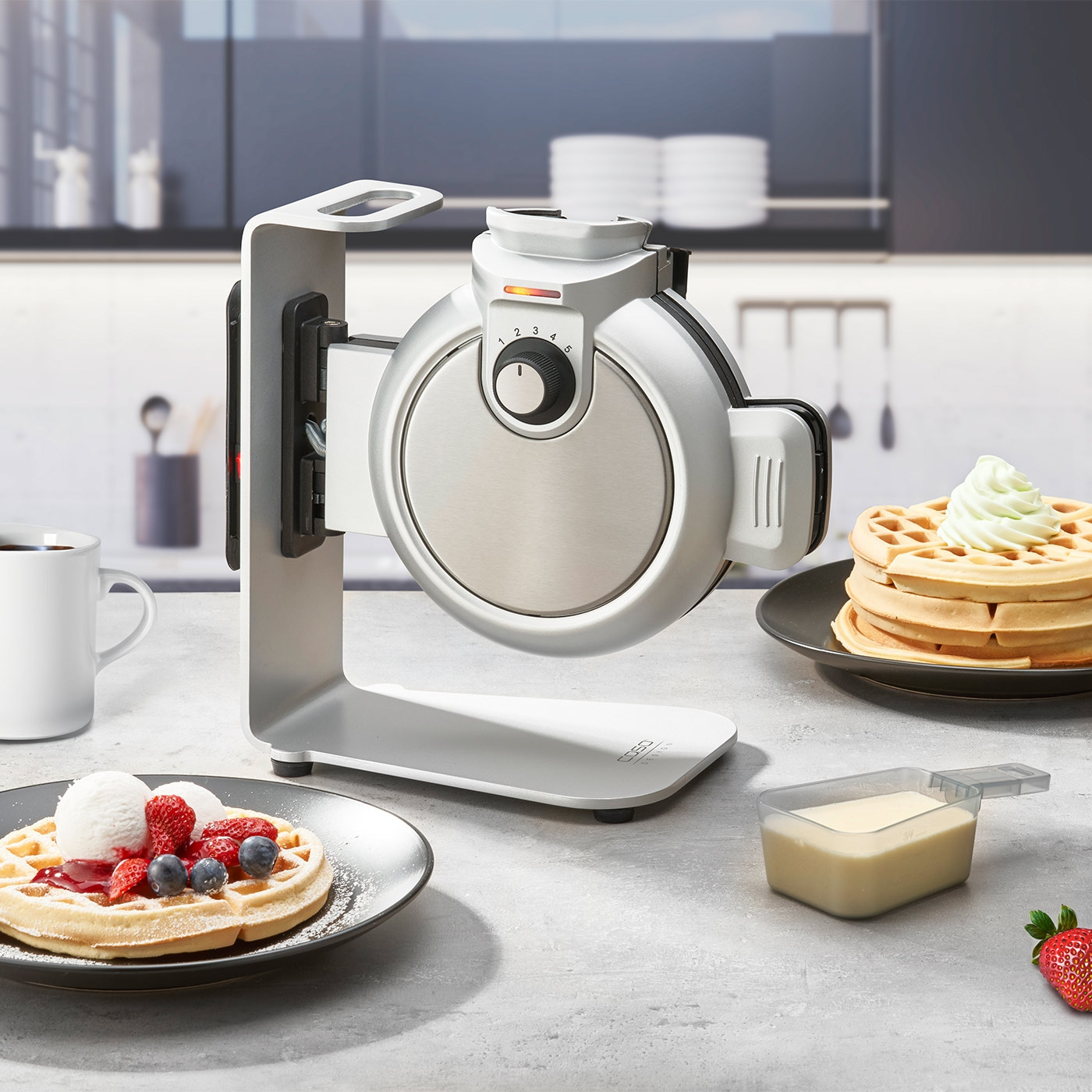 Waffeleisen mit Waffeln und Beeren auf einem Tisch in der Küche.