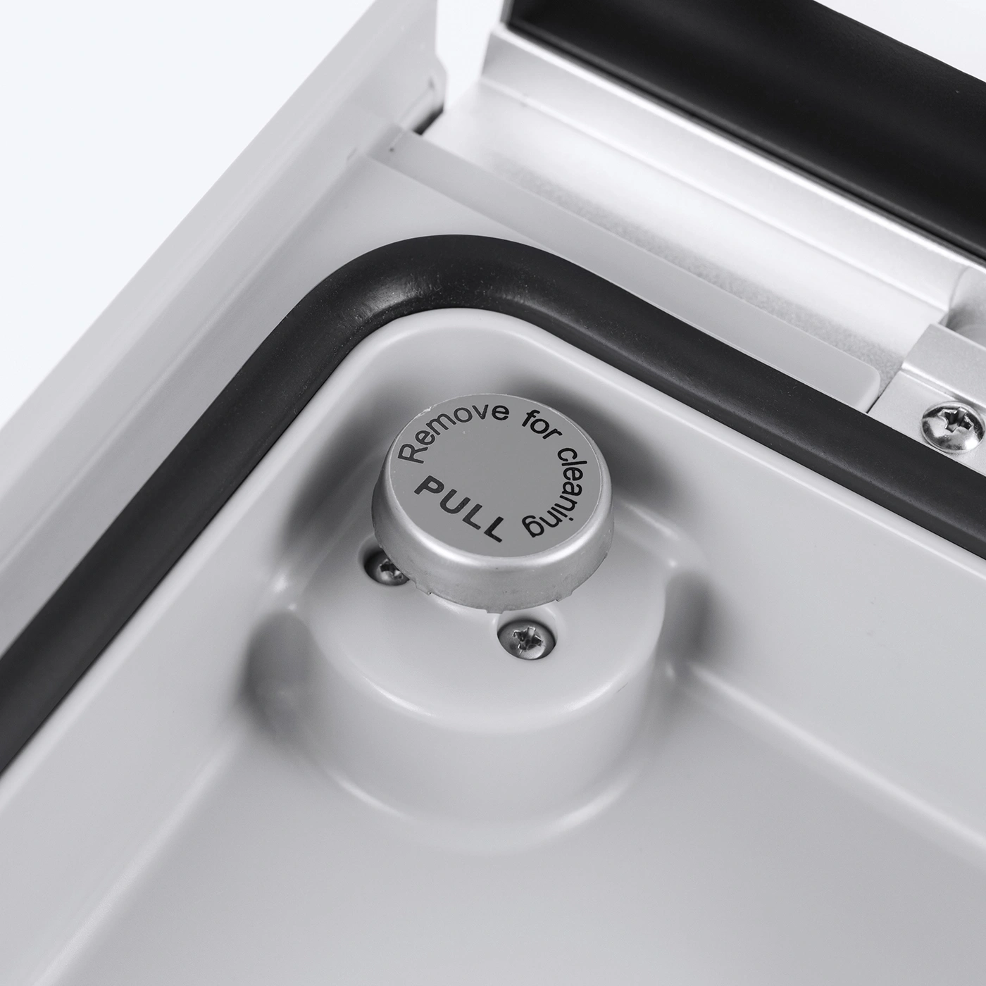 Ein silberner Knopf mit der Aufschrift "PULL" und "Remove for cleaning"