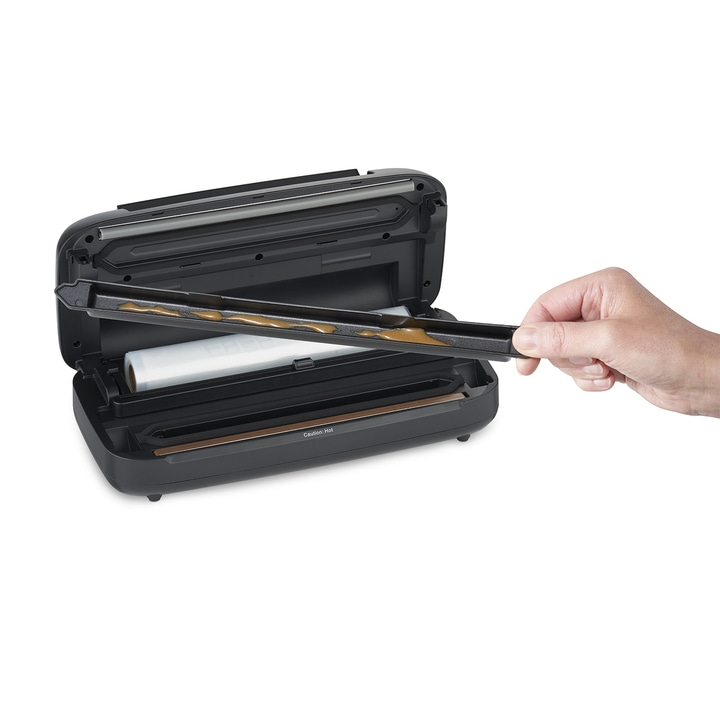 Vakuumiergerät, Hand hält Teil, offene Maschine, braune Flüssigkeit, weißer Hintergrund.