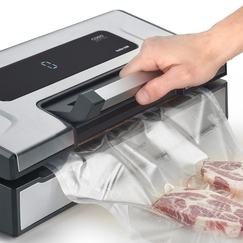 Mann bedient Vakuumiergerät mit Fleisch in Beutel