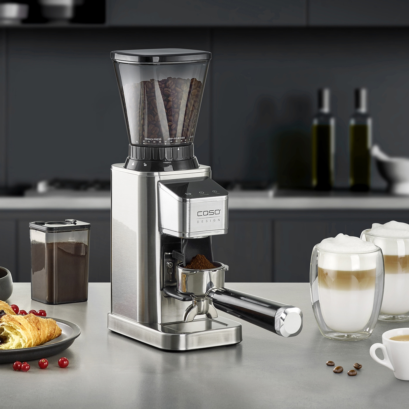 Kaffeemühle mit Zubehör, Kaffee, Croissant, Getränke auf einer Theke.