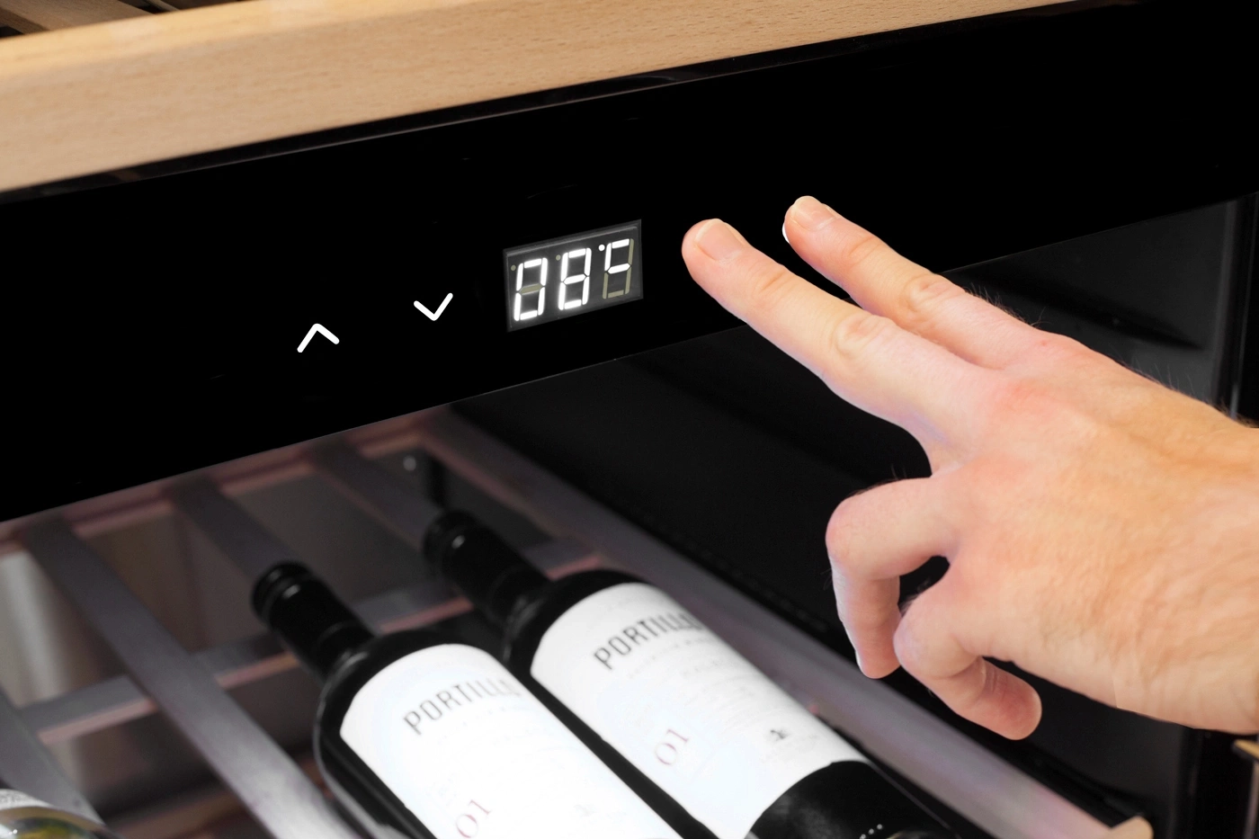 Ein Finger drückt auf die Steuerung eines Weinkühlschranks mit digitaler Anzeige.