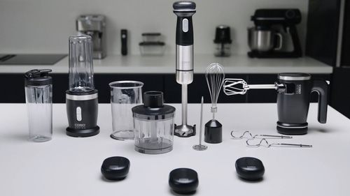 Küchengeräte auf weißem Tisch: Mixer, Stabmixer, Schneebesen, Handmixer, Zubehör.