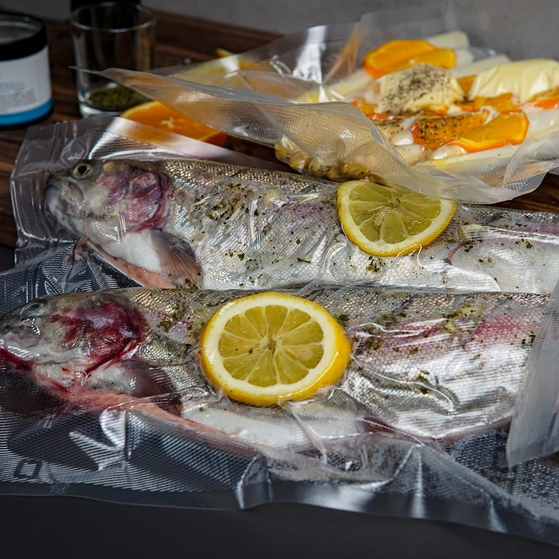 Zwei vakuumierte Fische mit Zitronenscheiben und Orangenstücken