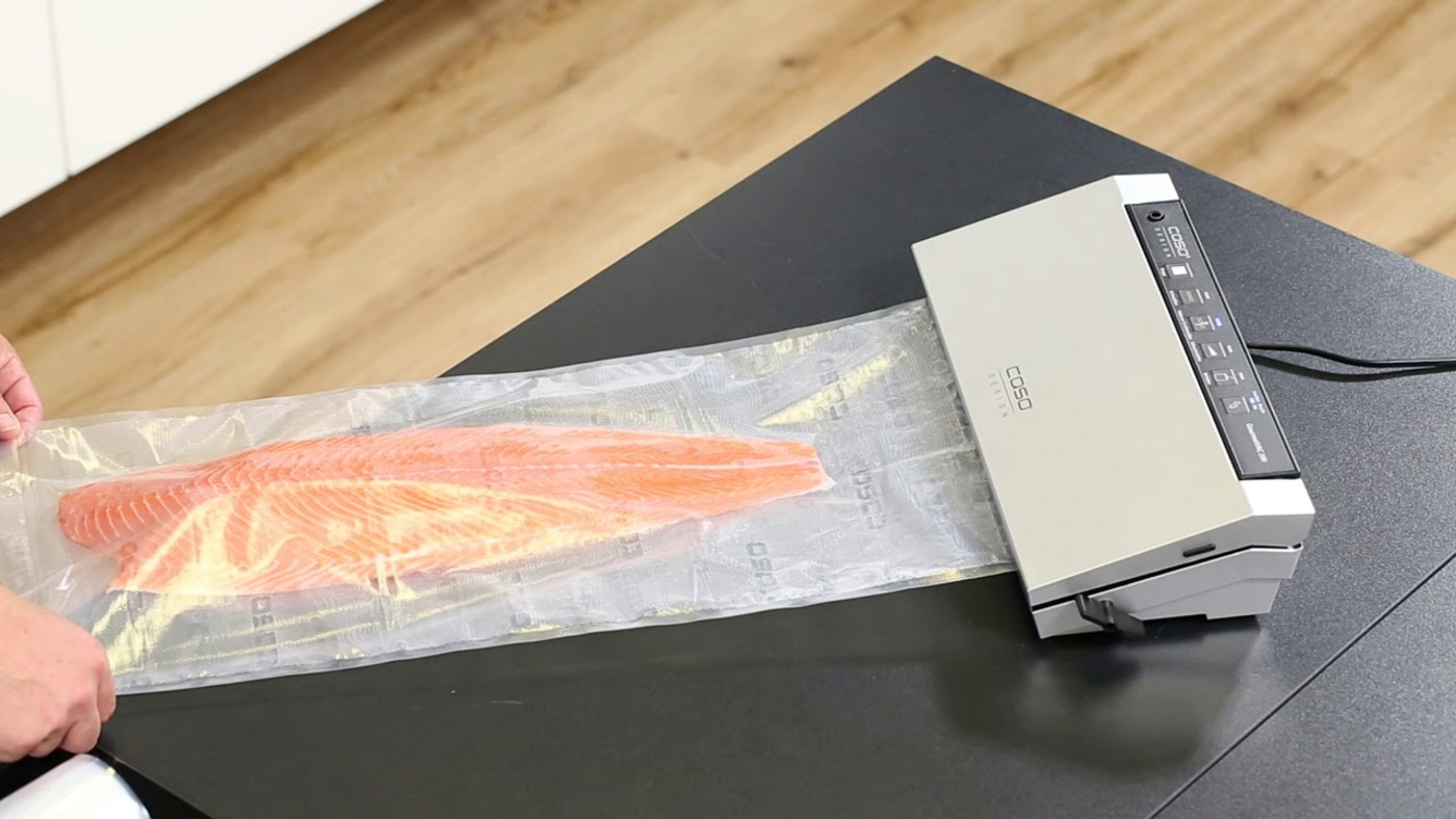 Lachsfilet wird mit einem Vakuumiergerät verpackt, um es frisch zu halten.