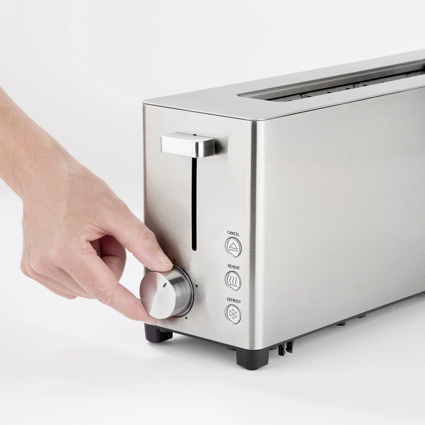 Hand turning the knob of a toaster to adjust the browning level of the bread.