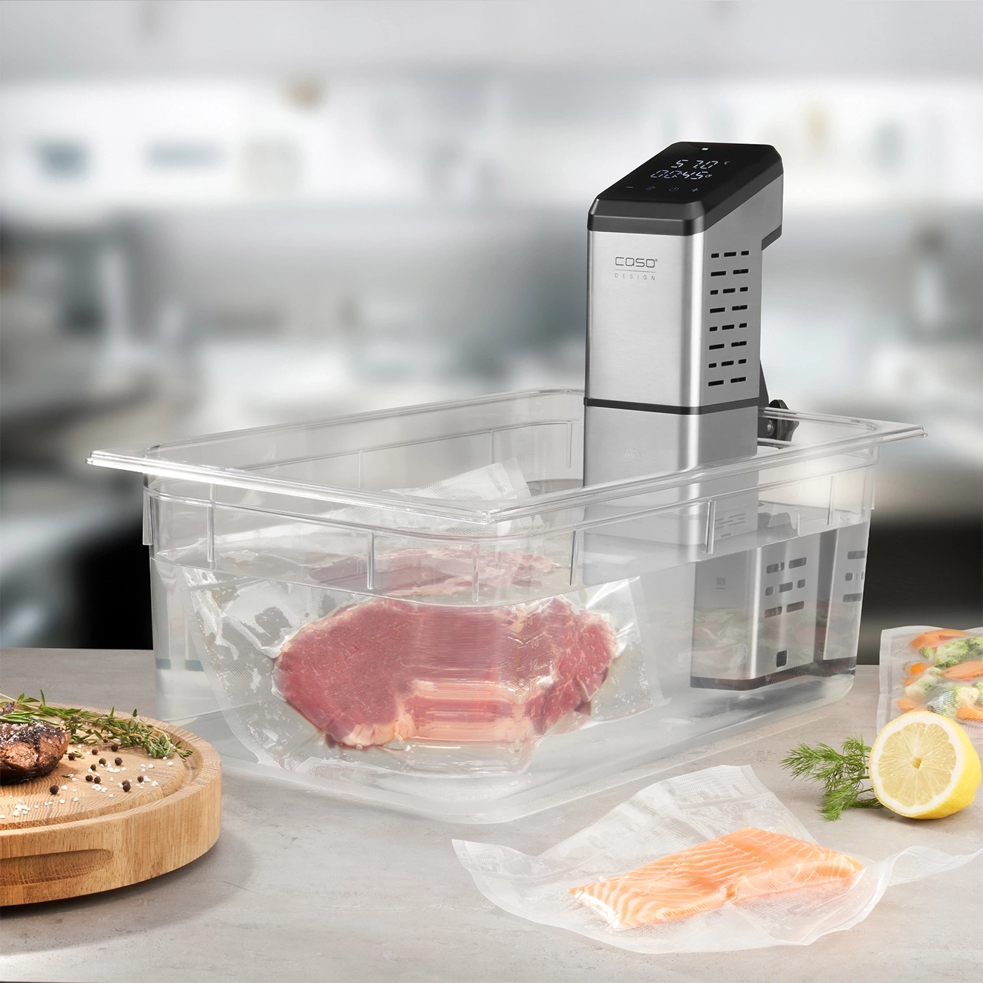 Machine sous vide avec viande et poisson en sachets, citron et herbes sur une table.