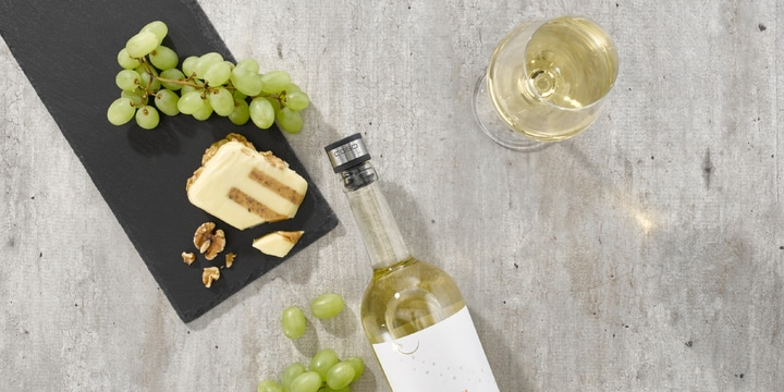 Weißwein, Trauben, Käse und Nüsse auf einem Tisch