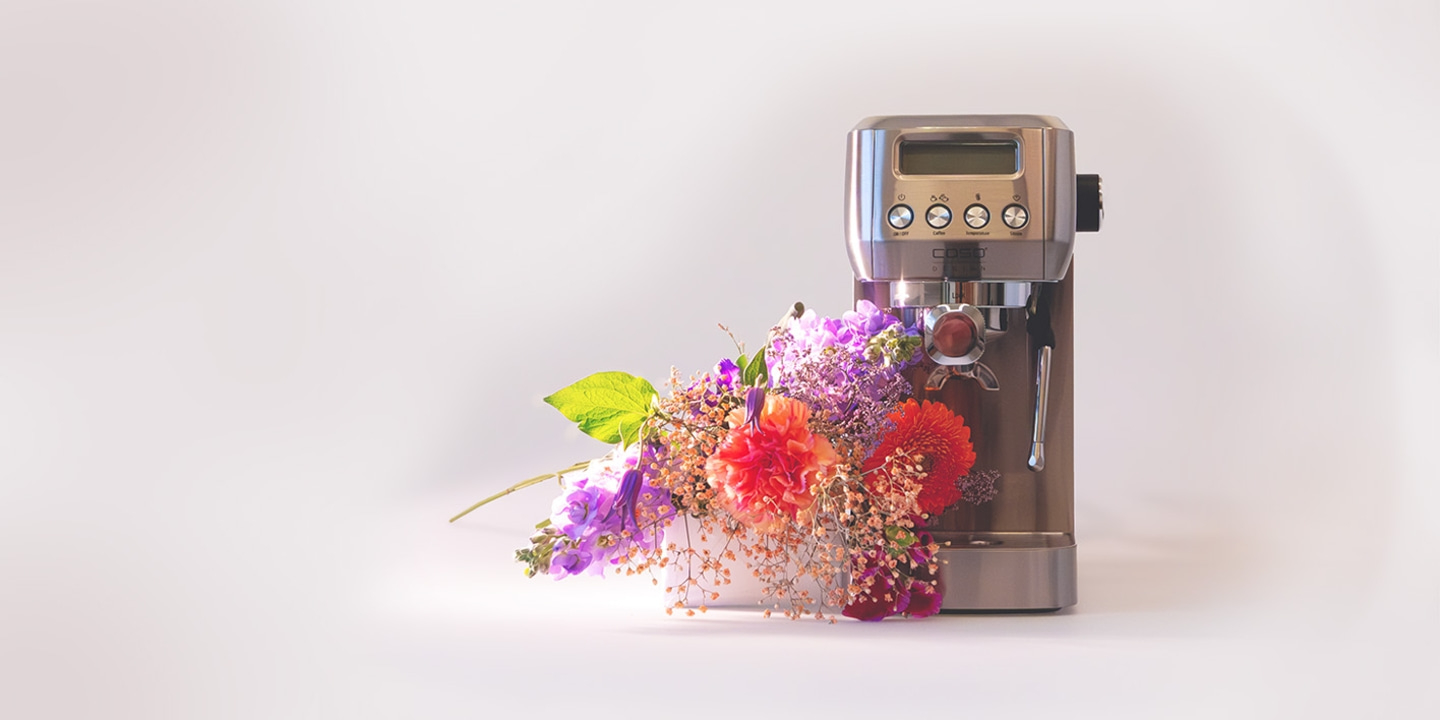 Espressomaschine mit Blumenstrauß auf hellem Hintergrund