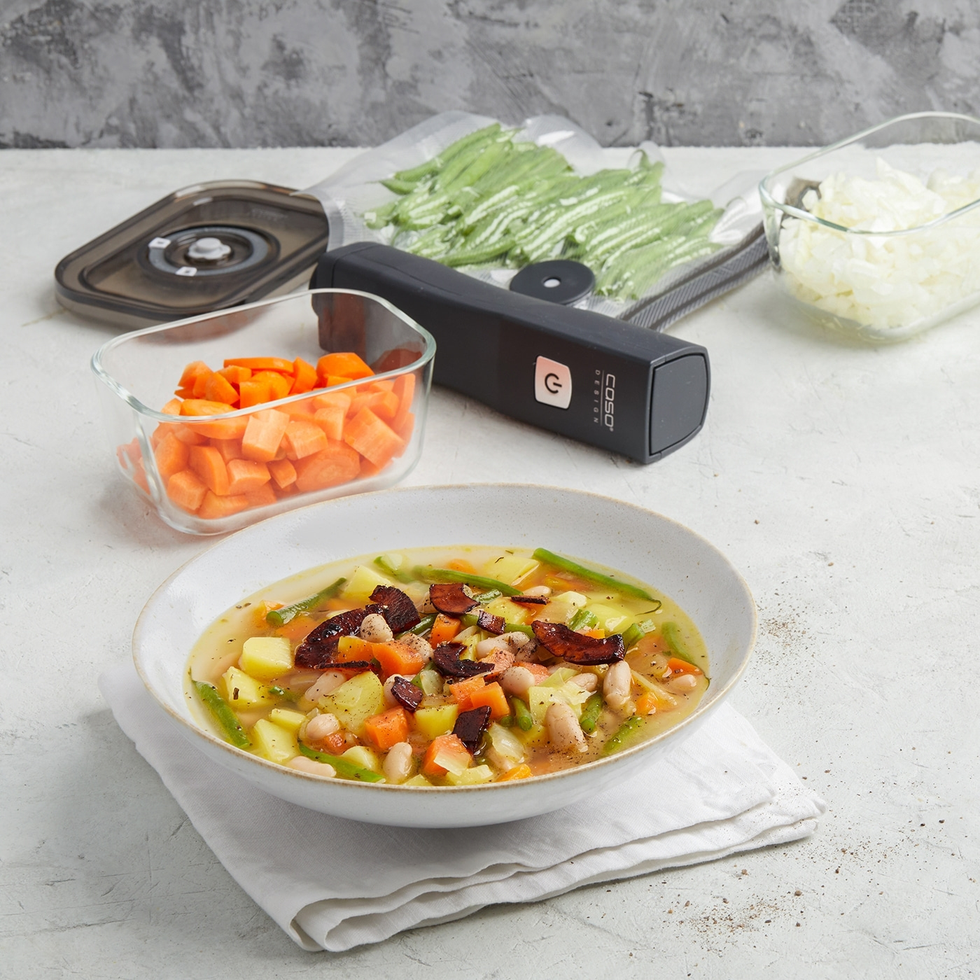 Gemüsesuppe mit Zutaten, Vakuumierer und Gemüse in Behältern