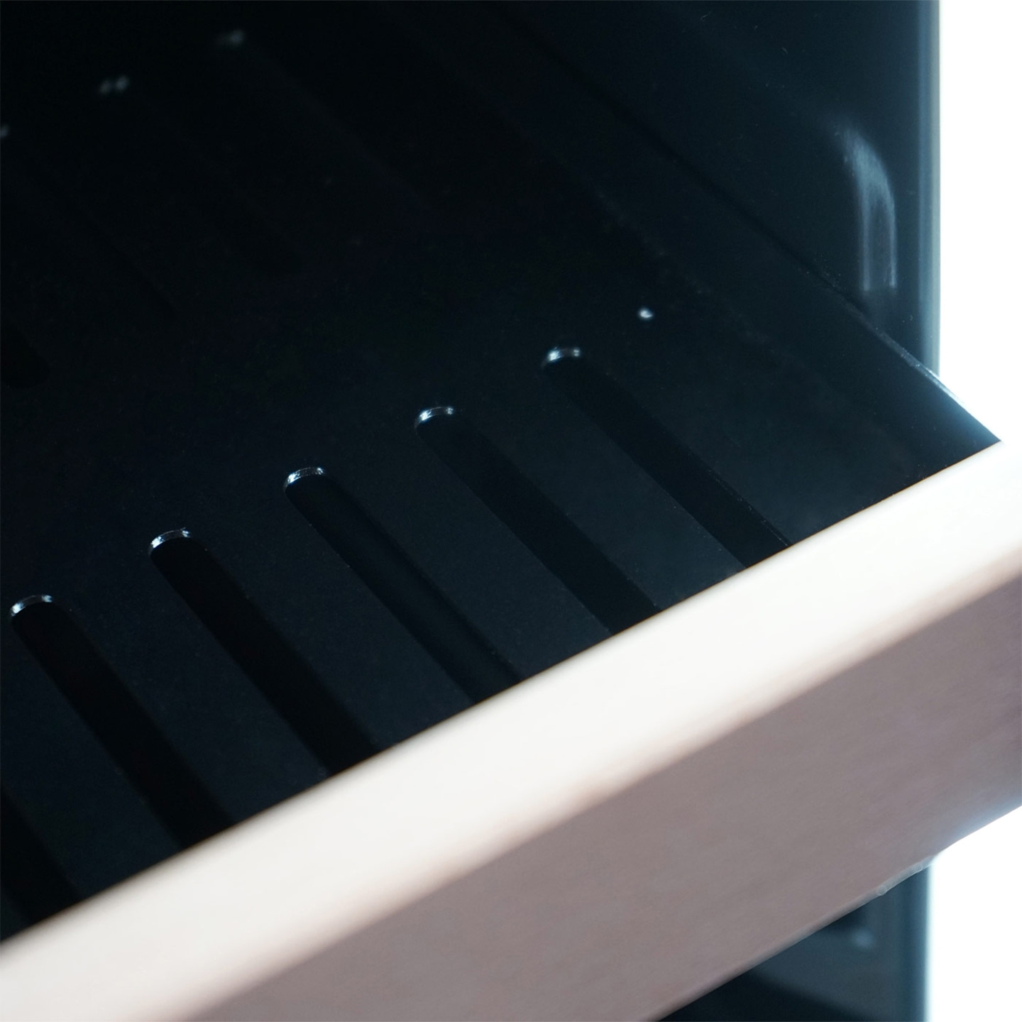 Nahaufnahme eines schwarzen Objekts mit hellbraunem Rahmen und Schlitzen