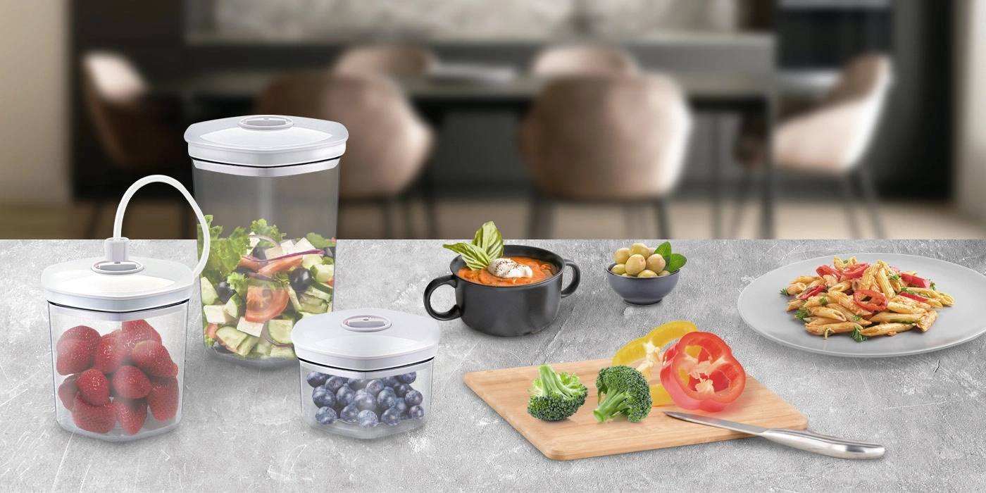 Vakuumbehälter mit Erdbeeren, Blaubeeren, Salat, Suppe, Oliven und Nudeln.