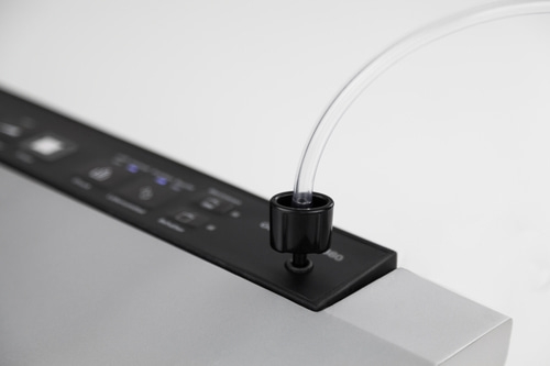 Gros plan d'un appareil noir avec un tube transparent qui en sort, sur fond blanc.