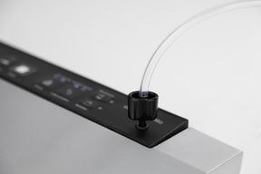 Gros plan d'un appareil noir avec un tube transparent qui en sort, sur fond blanc.