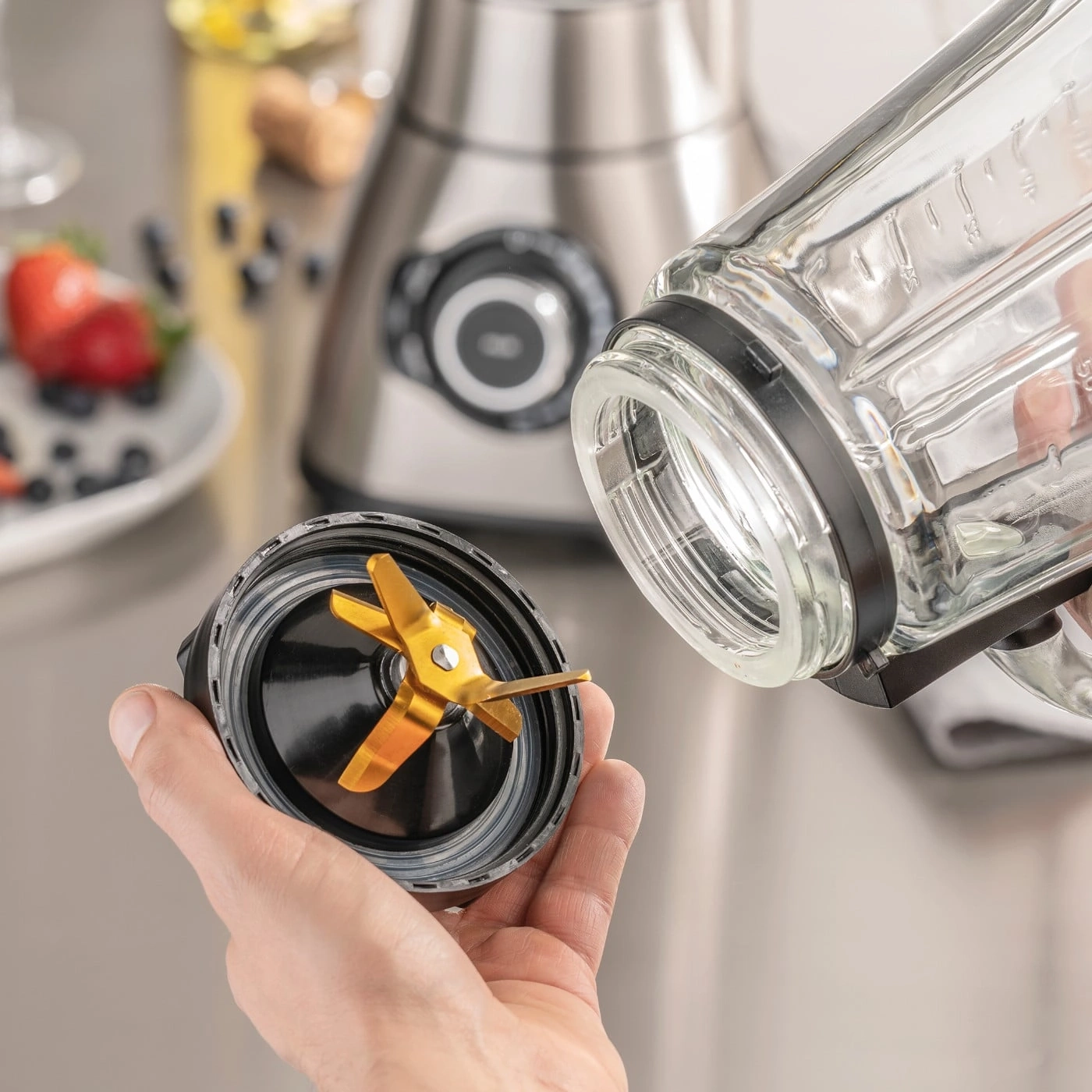 Close-up of a blender with blades and glass container being held in hand.