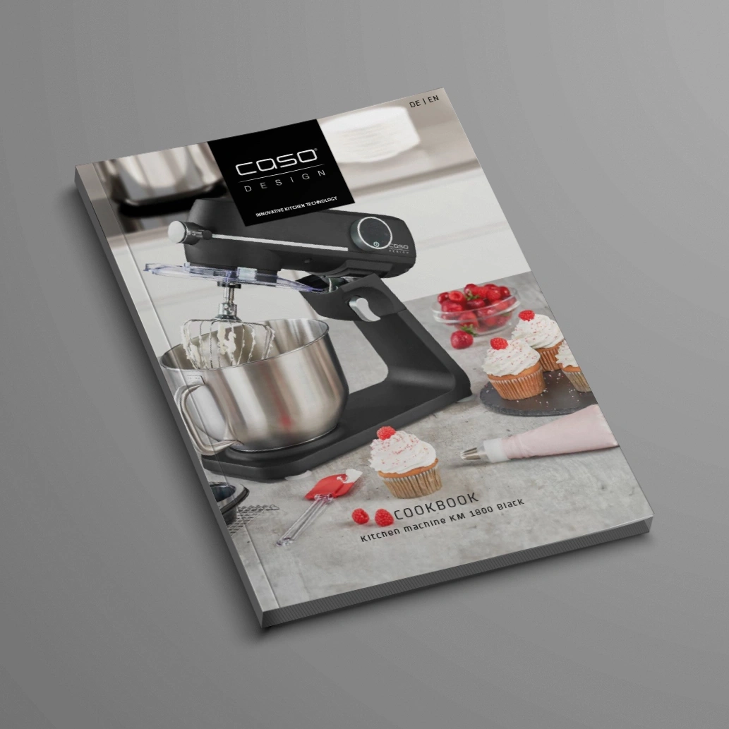Cookbook with kitchen machine and cupcakes on a grey background
