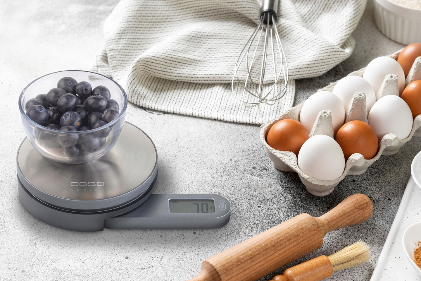 Blueberries on scale, eggs, whisk, baking ingredients, kitchen scene