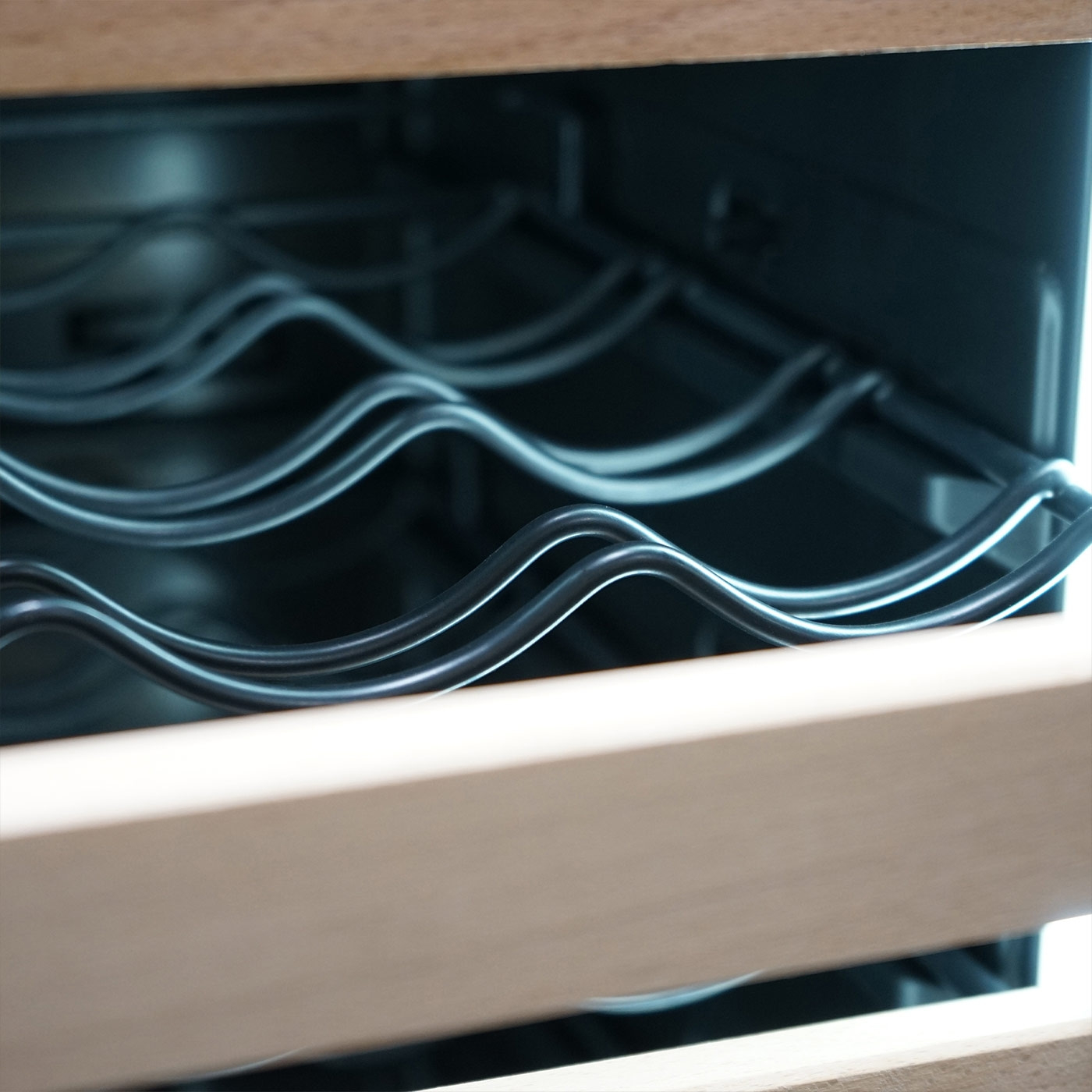 Close-up of a wine cooler with wavy metal racks and wooden frame
