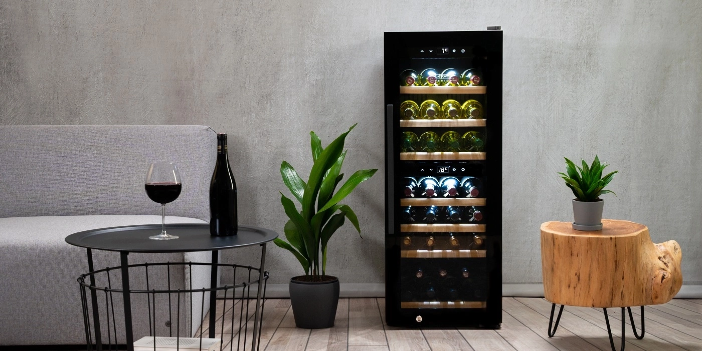 Ein Weinkühlschrank mit Flaschen und Gläsern daneben.