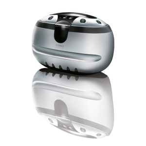 Silbernes Ultraschallreinigungsgerät mit ON/OFF-Tasten und Spiegelung auf weißem Hintergrund.