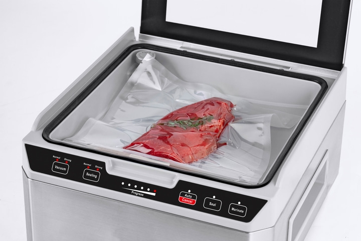 Vakuumiergerät mit Fleisch in einer Plastiktüte, bereit zum Versiegeln.