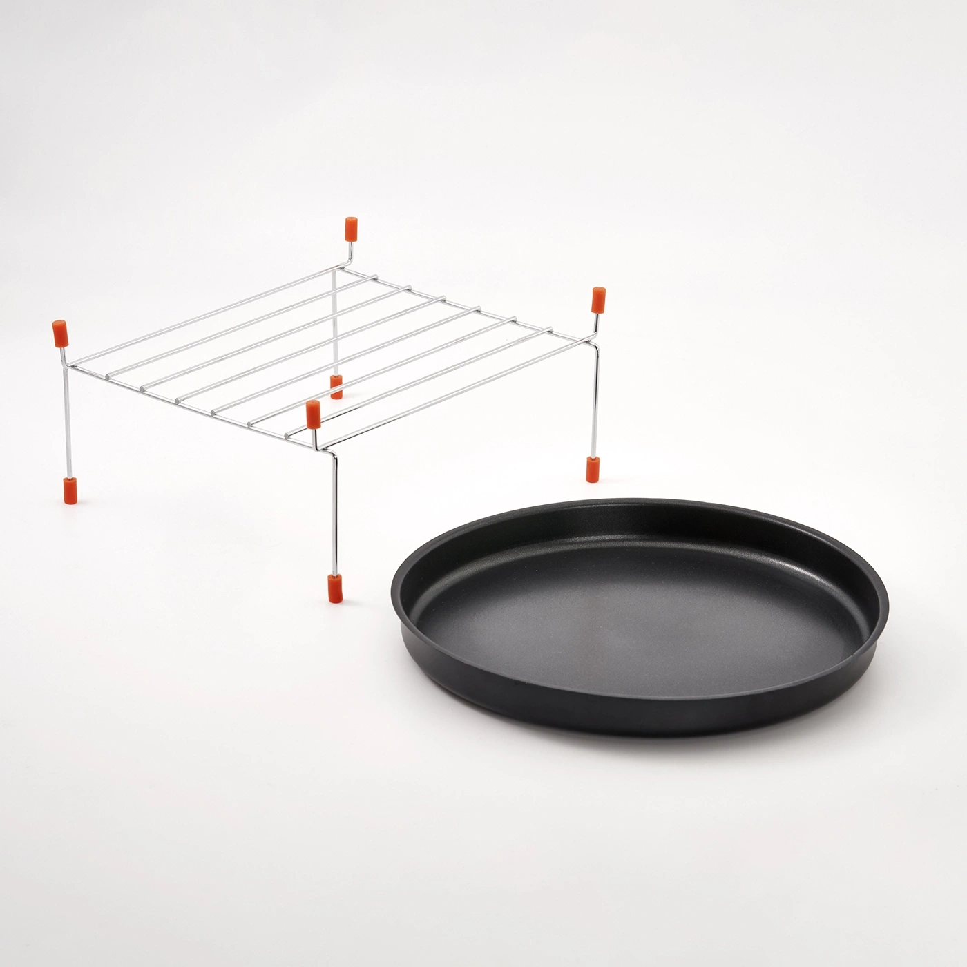 Ein Grillrost mit orangen Füßen neben einer schwarzen Bratpfanne.