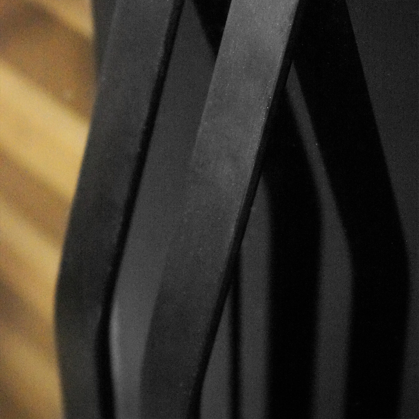 Schwarze, gebogene Metallstreifen vor einem Holzuntergrund, abstrakt