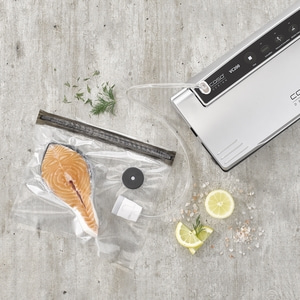 Salmon fillet in vacuum bag with lemon, herbs and vacuum sealer on concrete