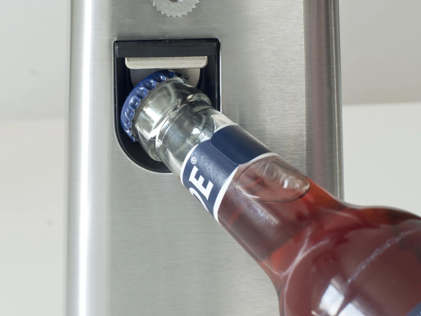 Flasche wird mit einem Flaschenöffner geöffnet, Nahaufnahme.