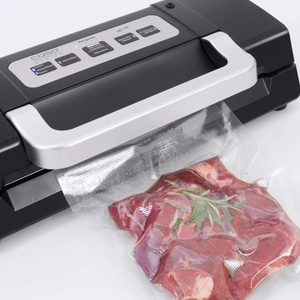 Scelleuse sous vide avec de la viande dans un sac, prête à être mise sous vide et scellée.