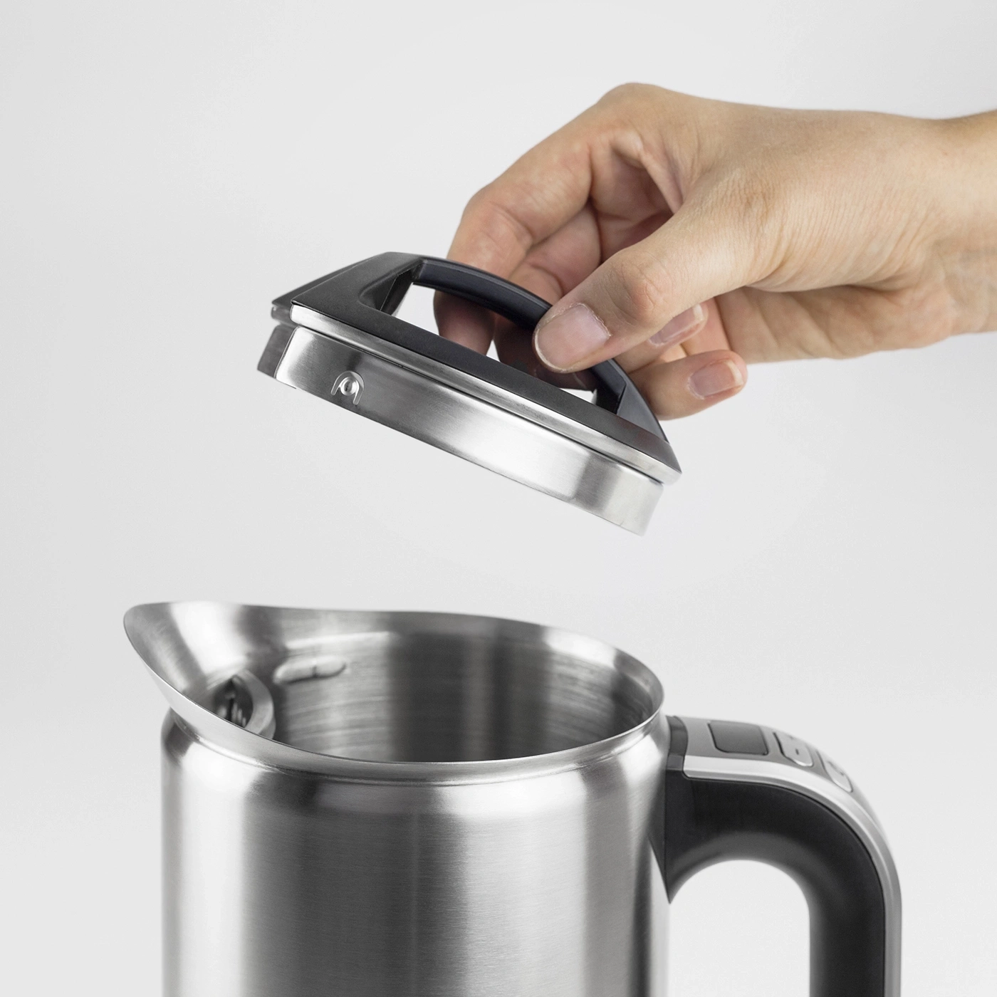Hand öffnet den Deckel eines Edelstahl-Wasserkochers, Nahaufnahme, isoliert
