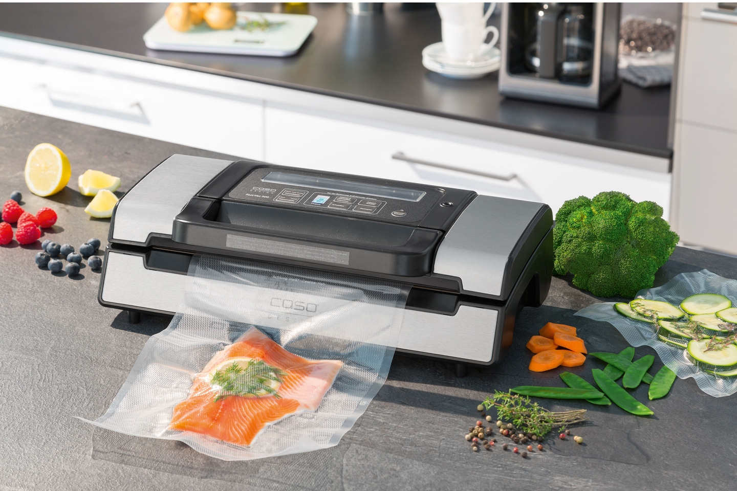 Vakuumiergerät mit Gemüse und Fisch auf einer Küchenarbeitsplatte