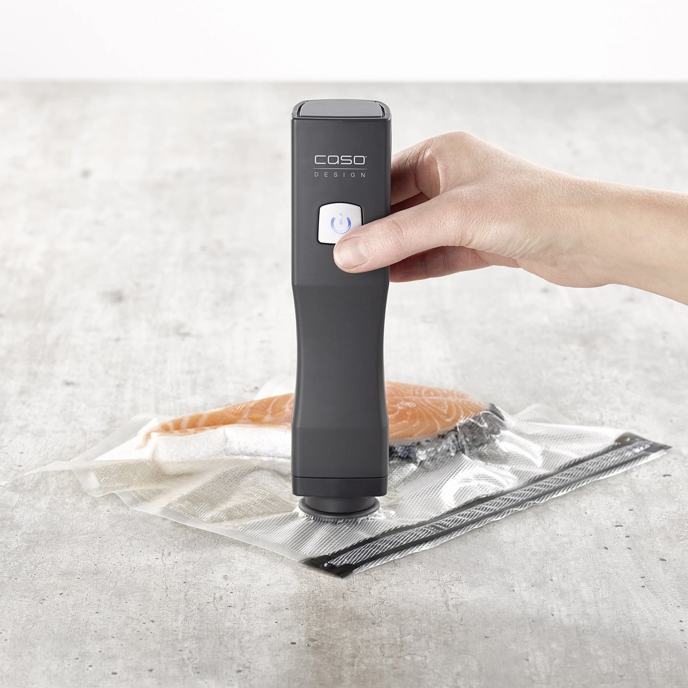 Scelleuse sous vide avec filet de poisson dans un sac plastique sur fond gris