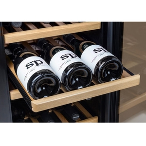 Wine bottles in a wine cooler. Label reads 'sp' and 'Aufwind 2014'. Wooden shelves.