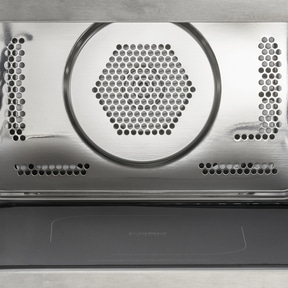 Close-up of microwave interior with metal grill and plate, modern design.