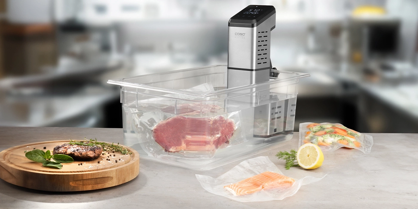 Sous-vide-Gerät mit Fleisch, Fisch und Gemüse in einem Wasserbad.
