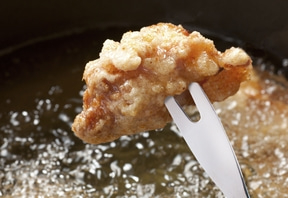 Frittiertes Essen wird mit einer Gabel aus dem Öl gehoben, knusprig und lecker.
