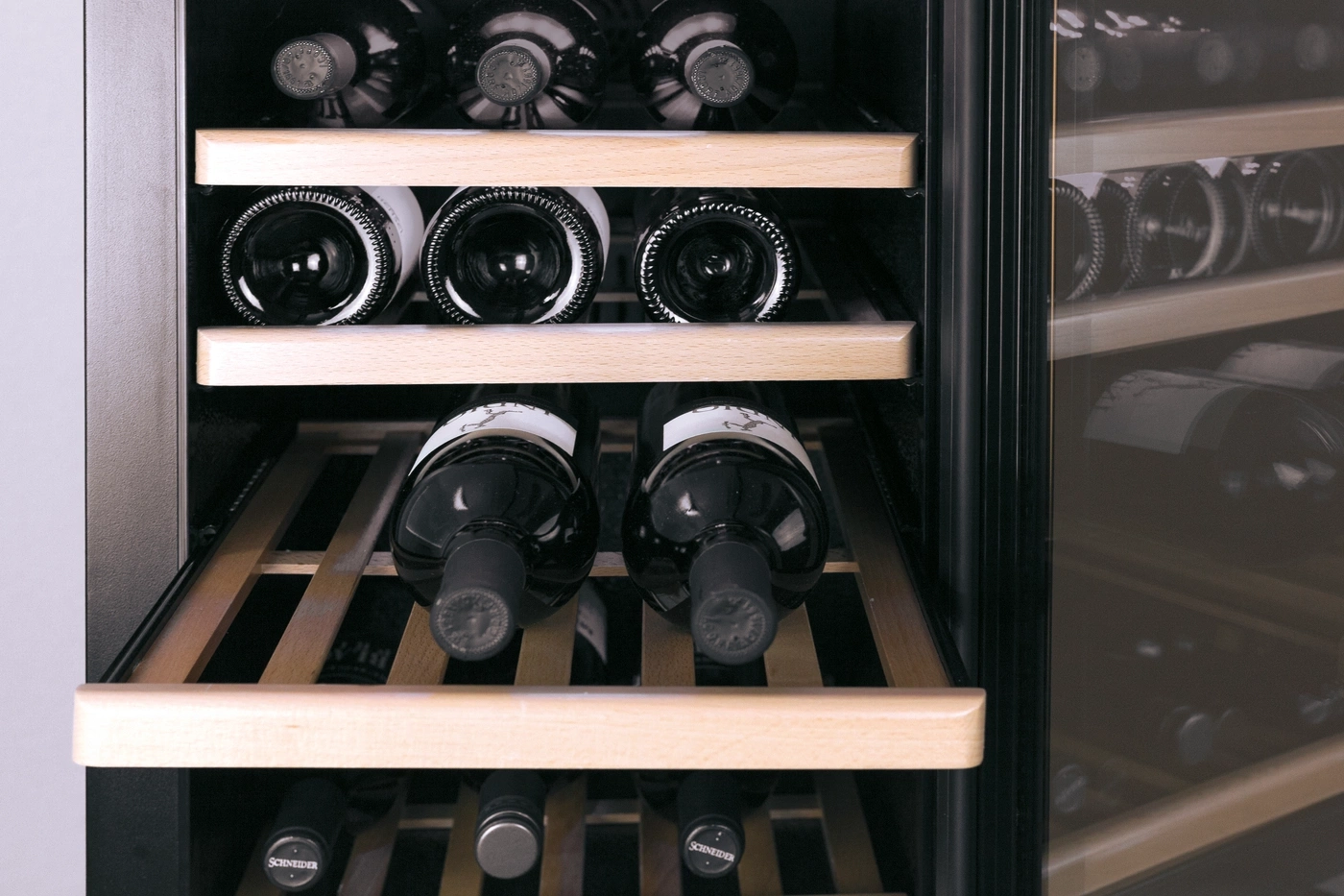 Weinkühlschrank mit mehreren Flaschen, Holzregalen und Glasfront.