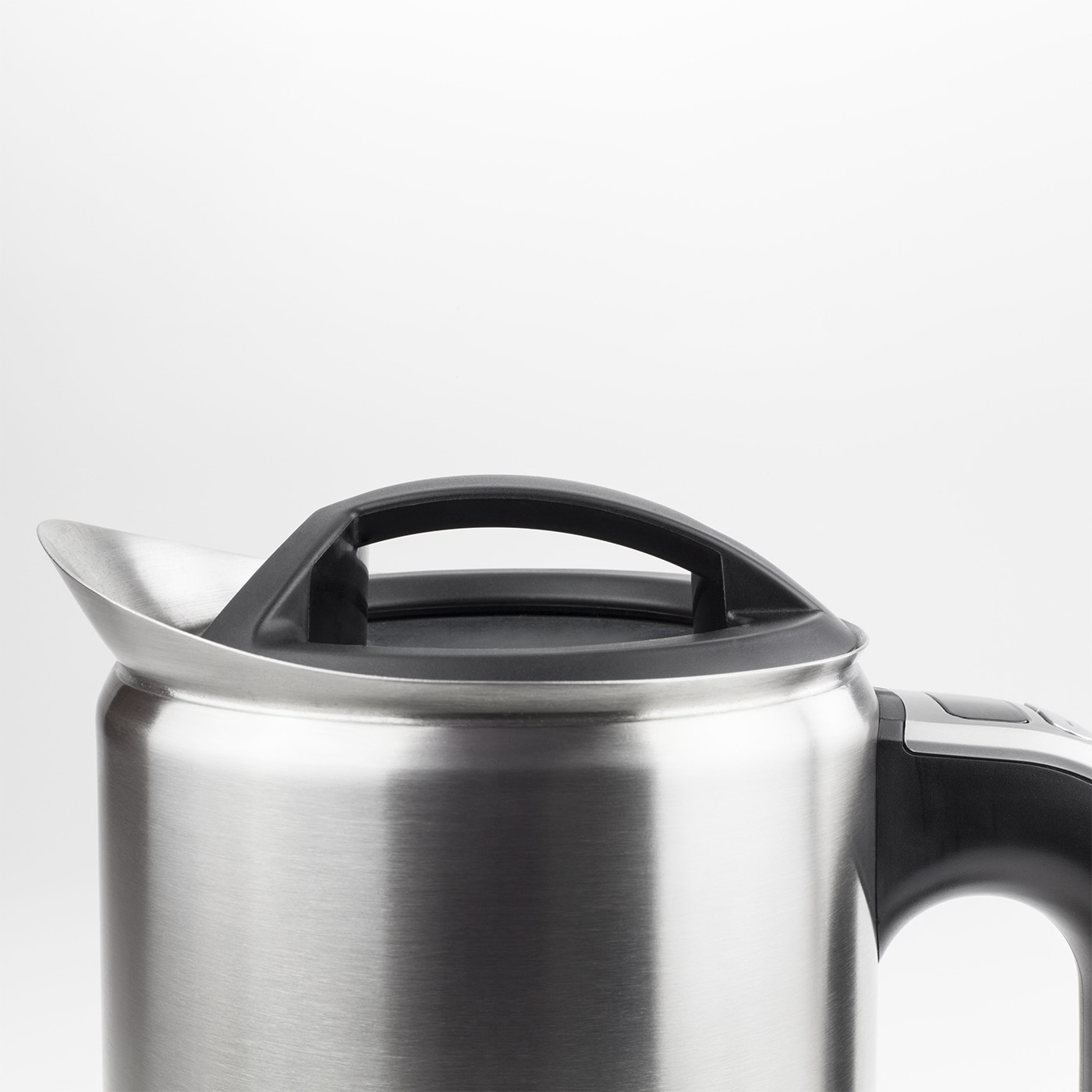 Gros plan d'une bouilloire argentée avec poignée et couvercle noirs