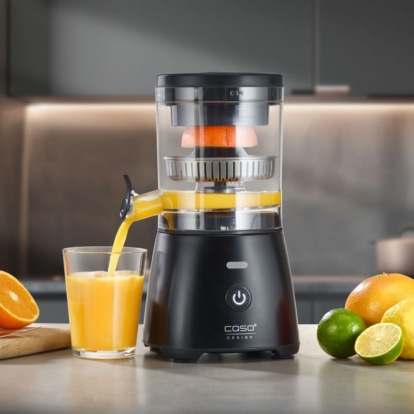 Un presse-agrumes électrique presse des oranges dans un verre sur un comptoir de cuisine.
