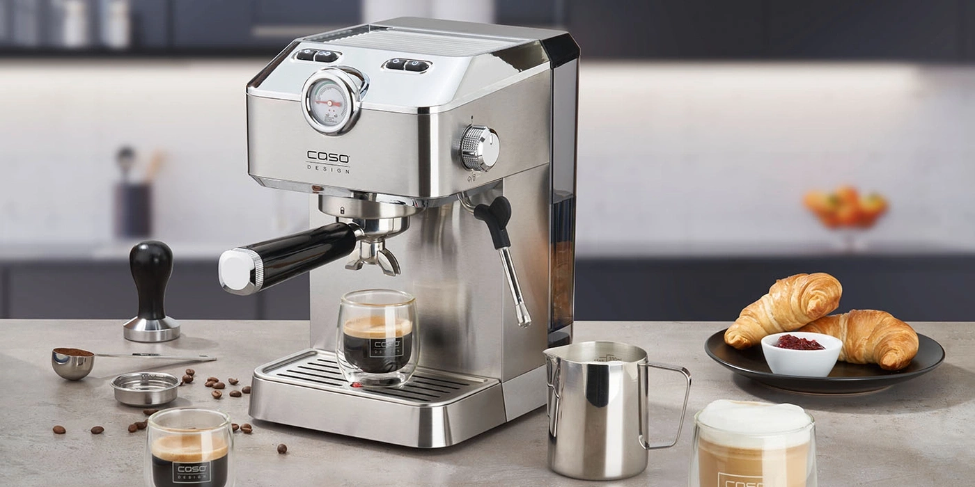 Kaffeemaschine mit Zubehör und Croissants auf einem Tisch in der Küche.