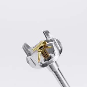 Gros plan d'un mixeur doré avec boîtier et tige argentés sur fond blanc