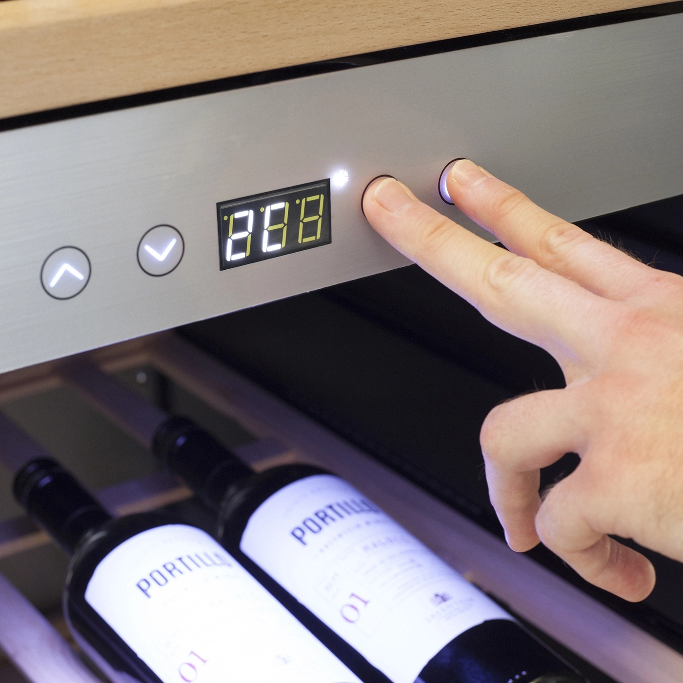 Ein Mann bedient ein digitales Display an einem Weinkühler mit zwei Fingern.