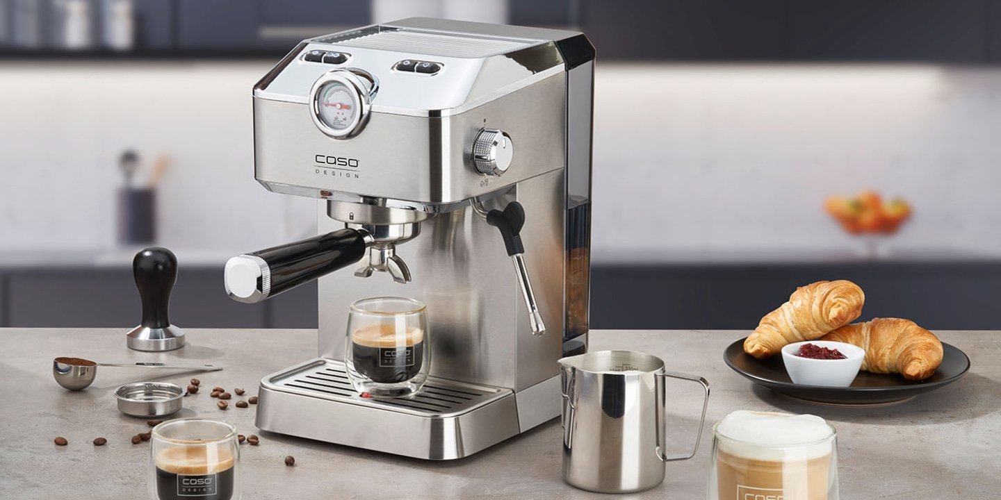 Kaffeemaschine mit Zubehör und Croissants auf einem Tisch in der Küche.