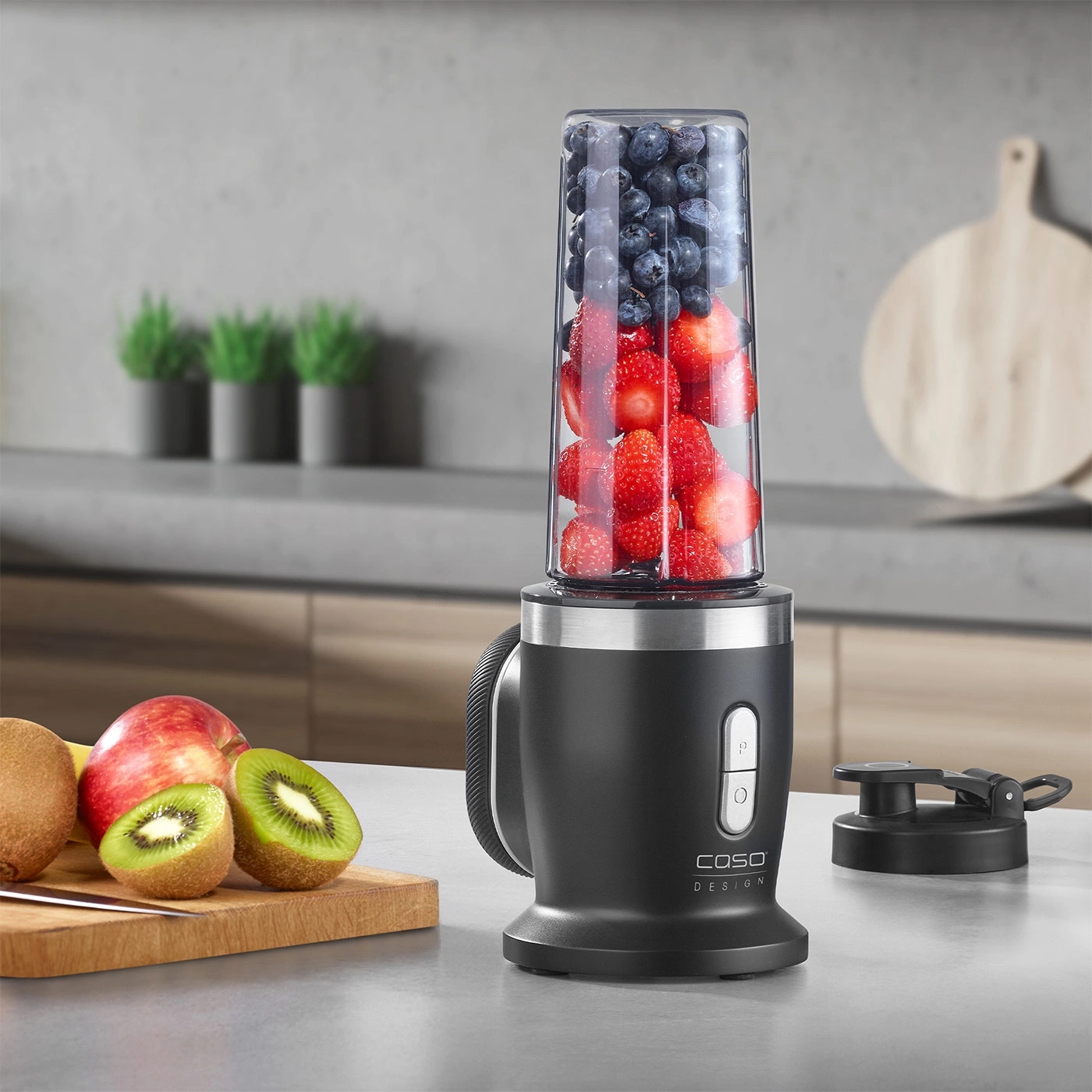 Mixer mit Früchten, Apfel, Kiwi, Erdbeeren und Blaubeeren auf der Arbeitsplatte