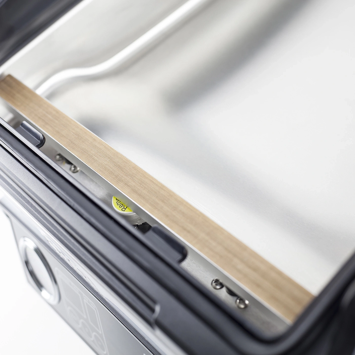 Close-up of a vacuum sealer machine with sealing tape and metal surface.