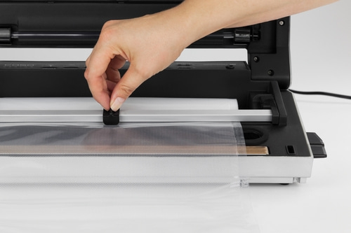 Main actionnant une machine à sceller sous vide, fermant un sac, gros plan, appareil