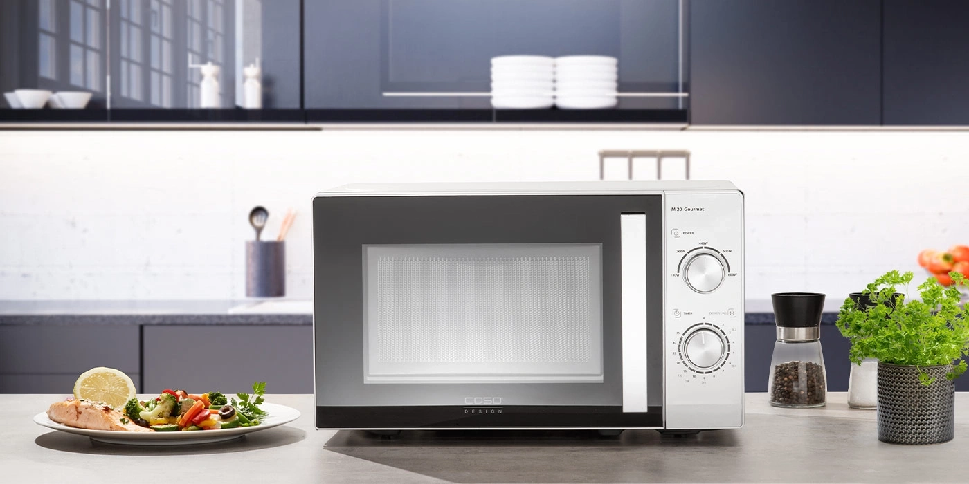 Eine Mikrowelle mit Essen und Gewürzmühle in einer modernen Küche.