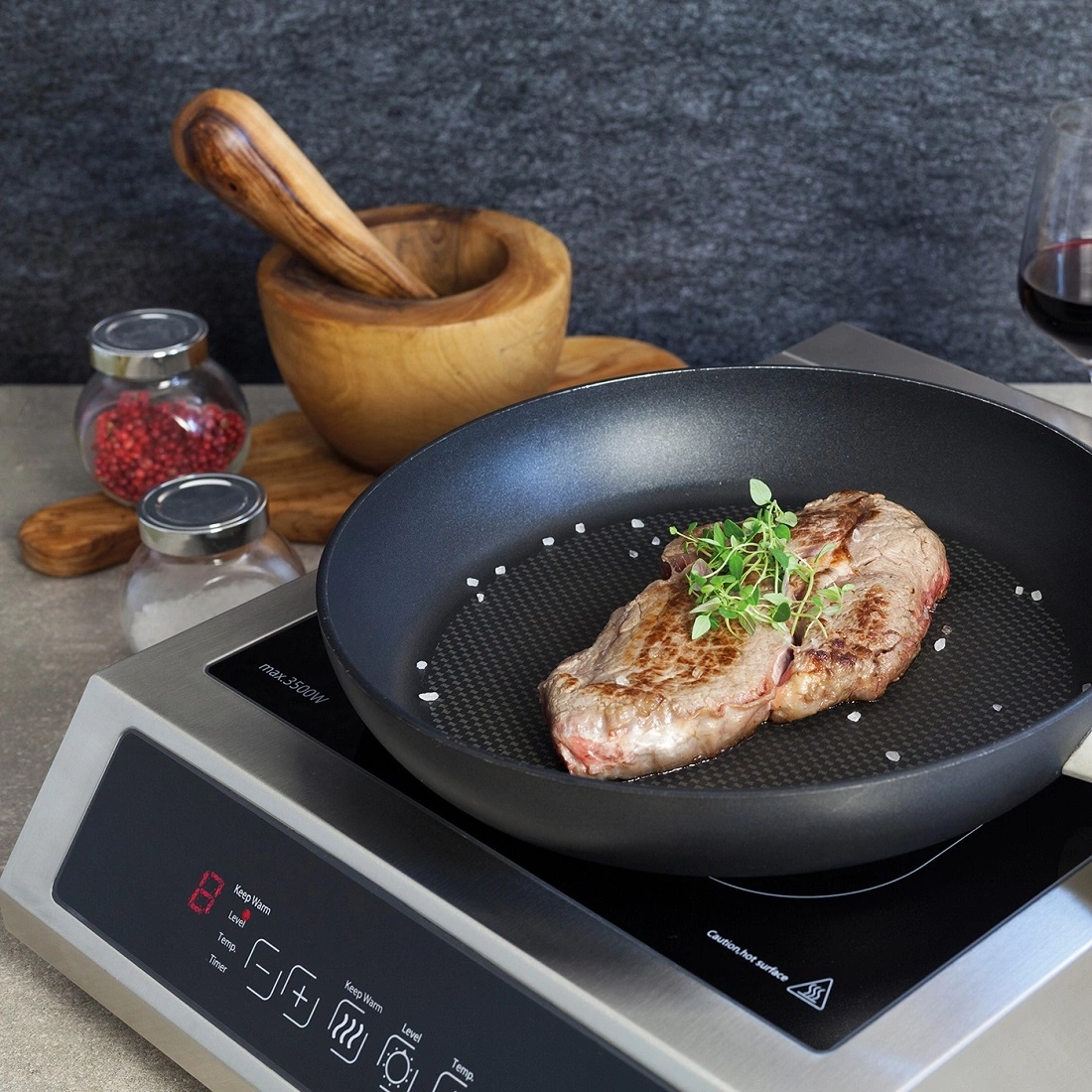 Ein Steak wird in einer Pfanne auf einem Induktionskochfeld gebraten.